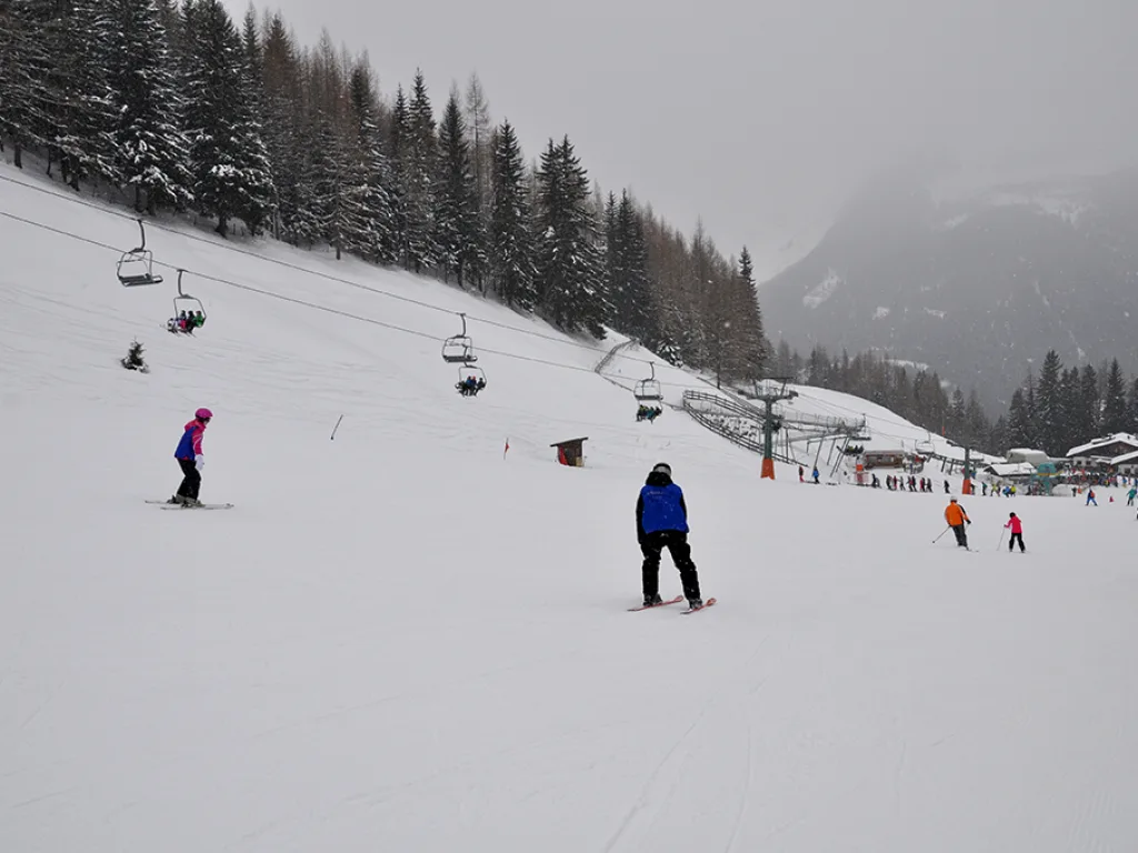 Skifahrende auf der Piste unterhalb des Sessellifts.